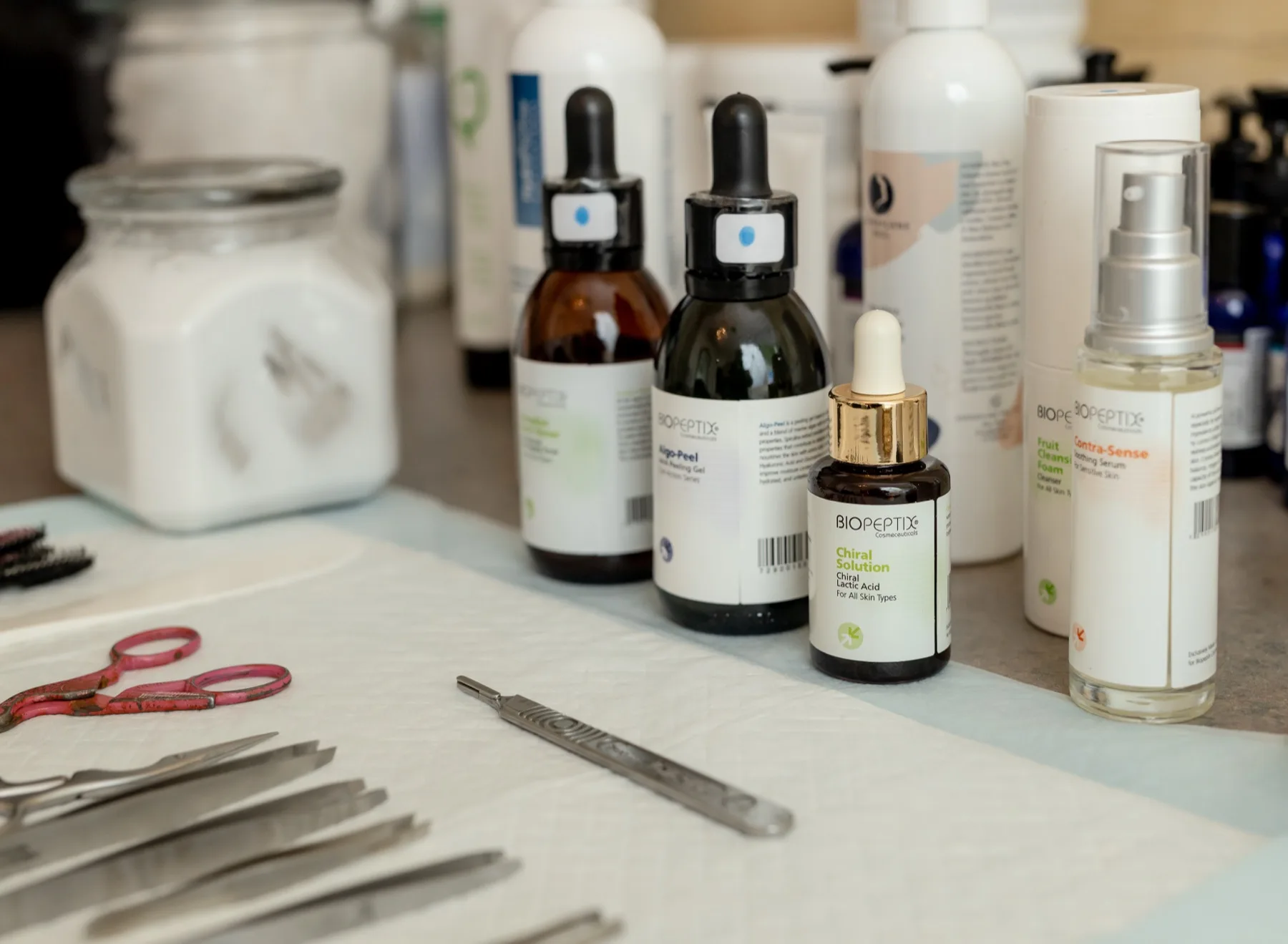Amber serum droppers and skincare bottles set out on a freshly prepared treatment table, beside sterilized tools on a clean cloth.