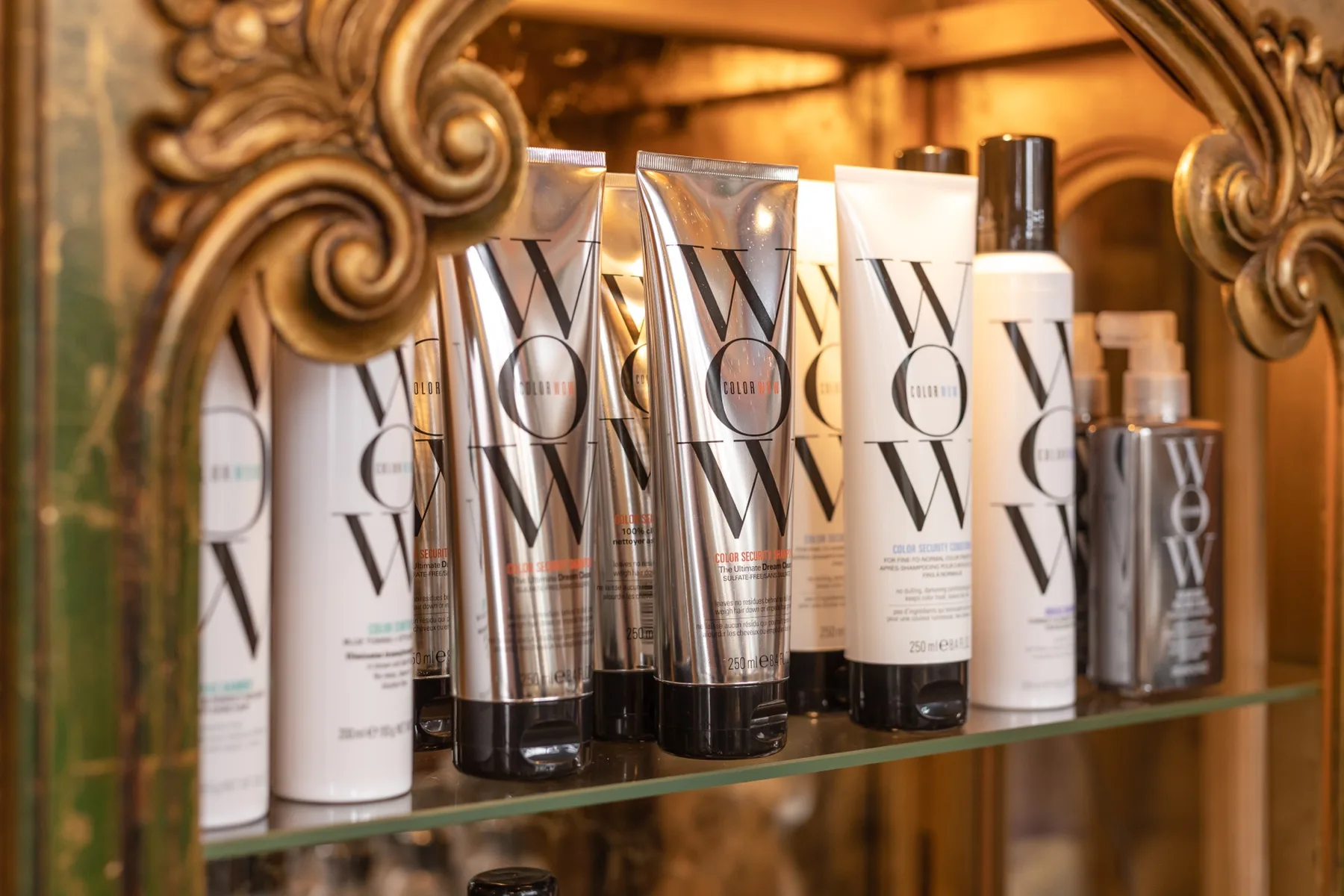 Color Wow hair care lined up on a glass shelf framed by an ornate gilded mirror at ESSpa Kozmetika