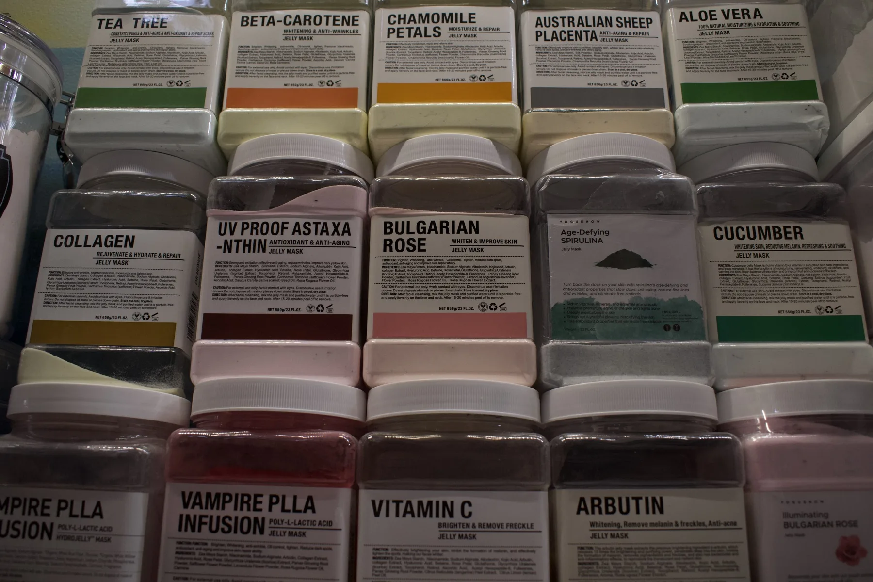 Rows of labeled ESSpa jelly mask jars filling a lit retail case, from Tea Tree and Chamomile Petals to Bulgarian Rose, Collagen and Vitamin C.