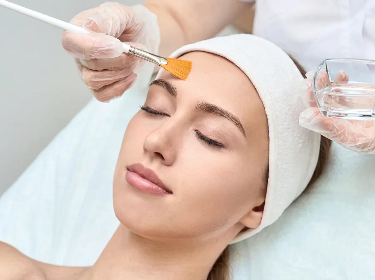 Esthetician applying a chemical peel with a brush during an anti-aging skin peel