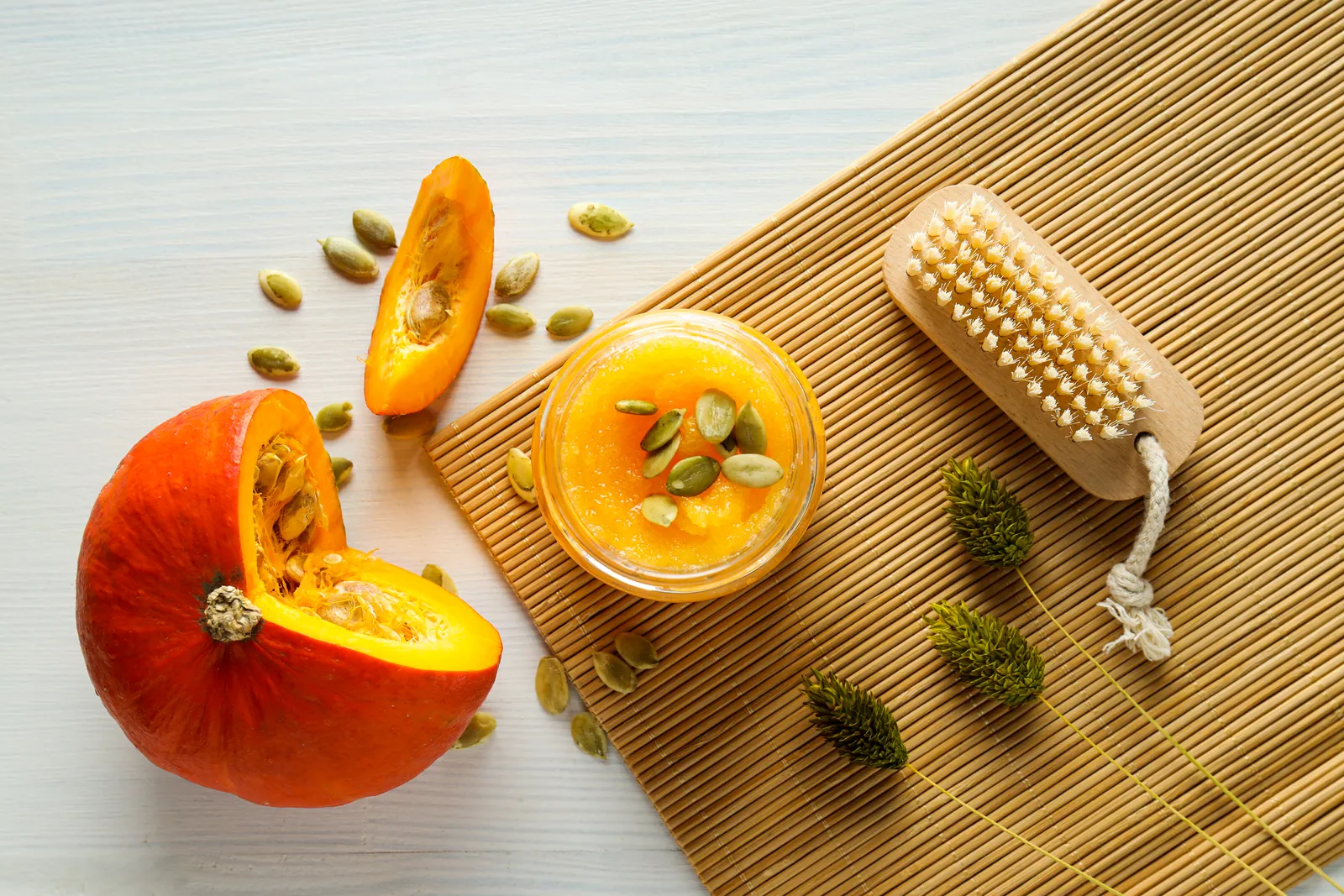 Fresh pumpkin with a pumpkin scrub and a facial brush for a seasonal pumpkin facial